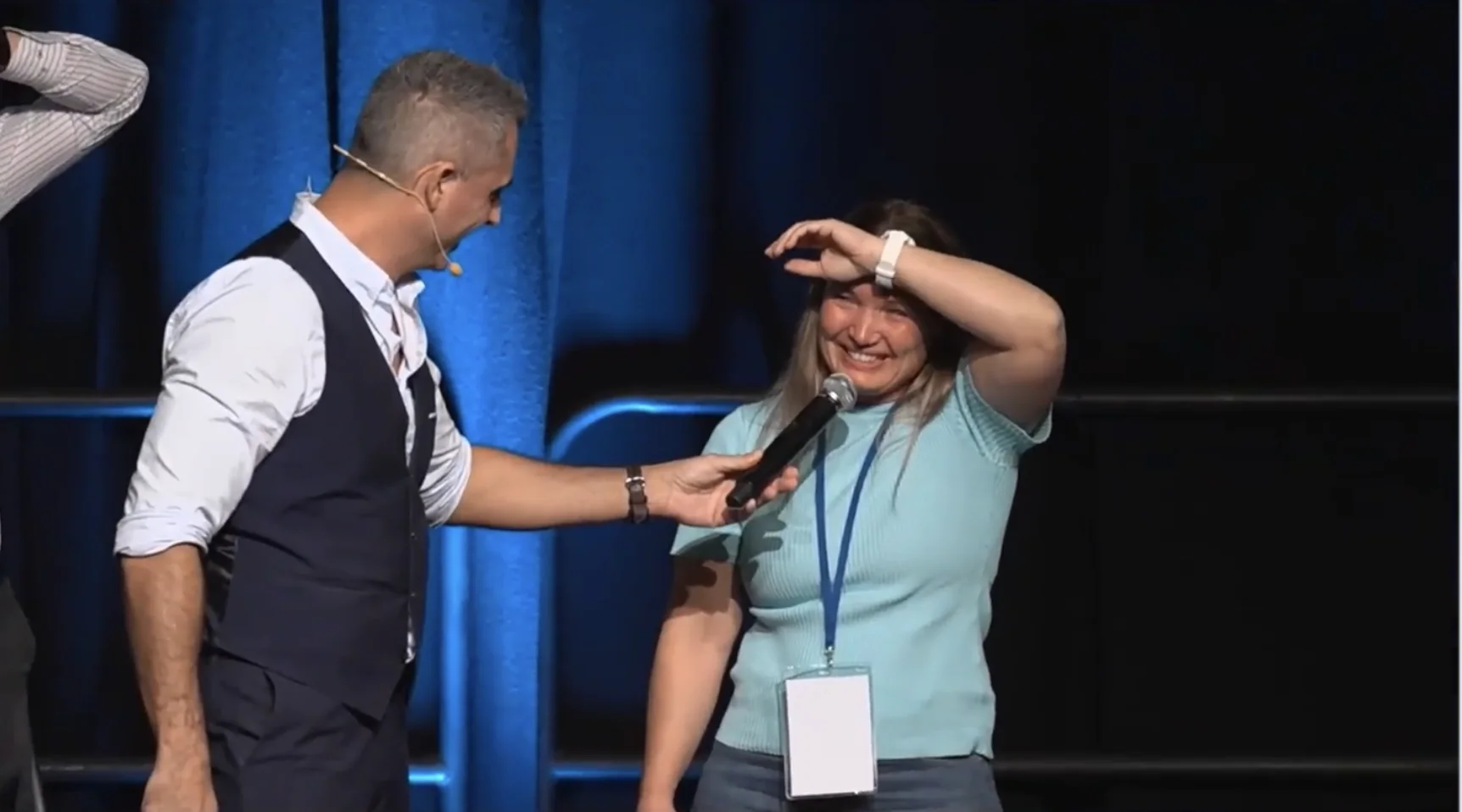A volunteer laughs as her hand sticks to her head during the MindSet keynote at a corporate conference